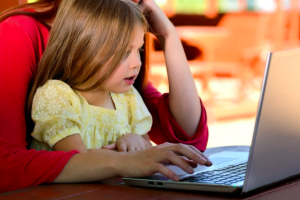 girl virtually learning on computer with mother